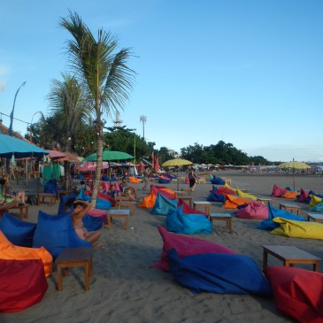 A balinese beach with colored bean bags and umbrellas